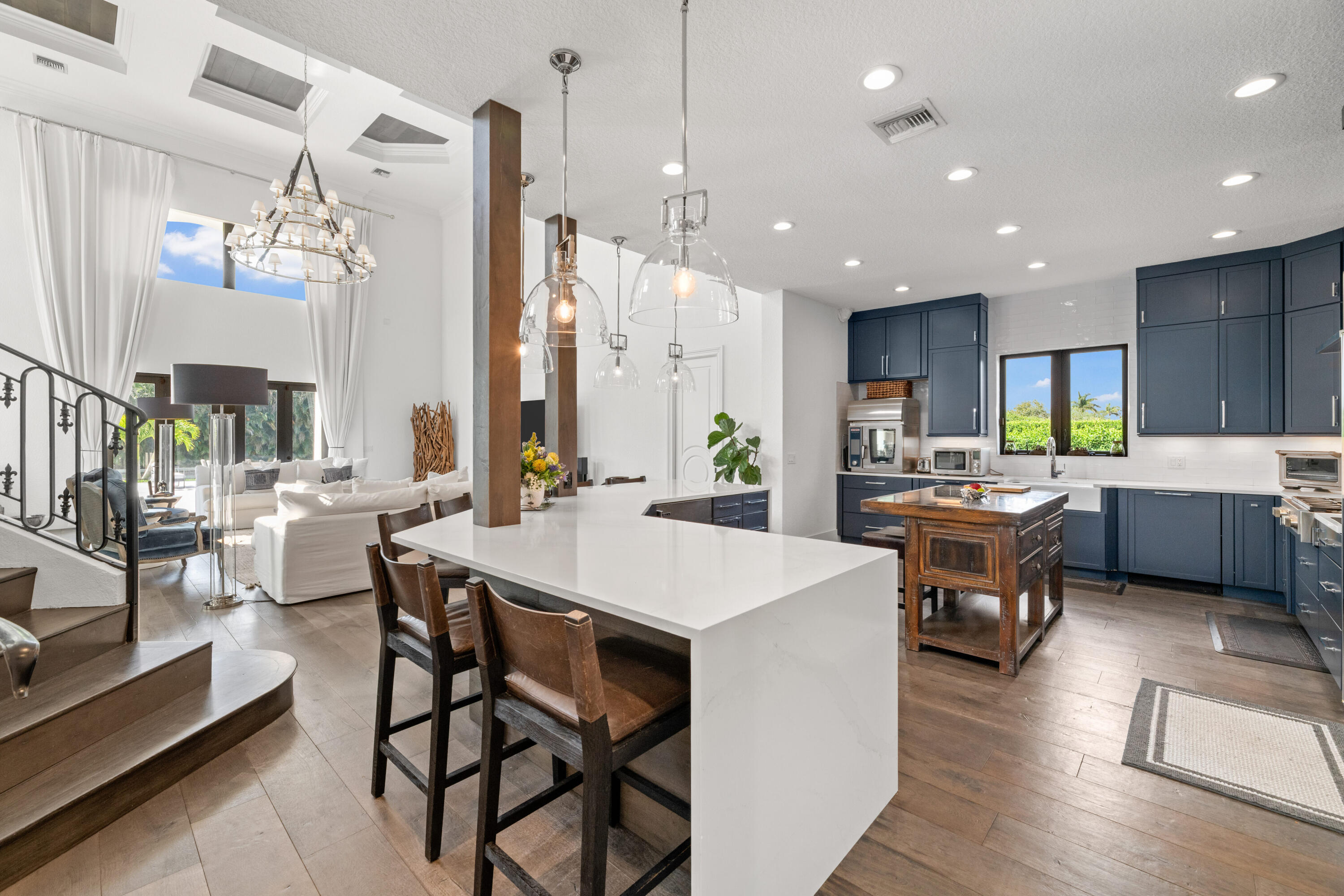Open-plan kitchen with navy cabinets, a large white island, and an adjoining bright living area.