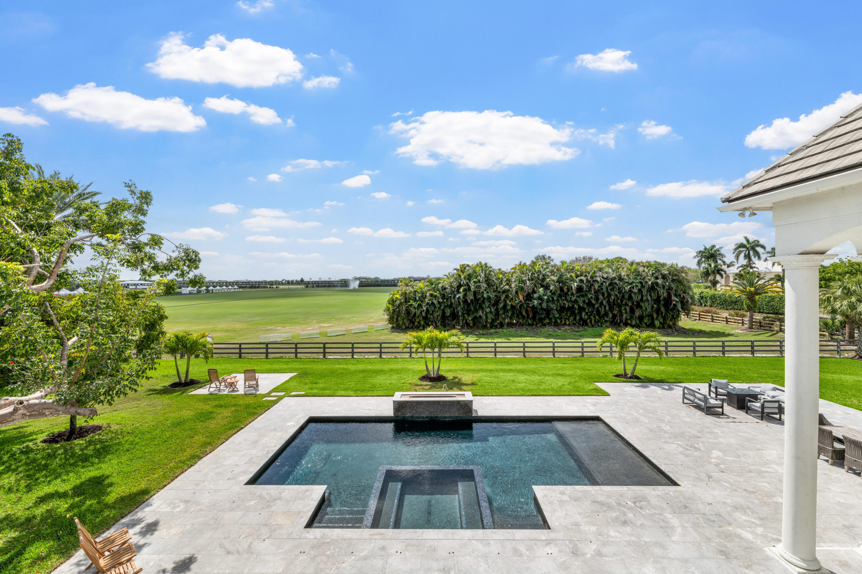 Backyard pool and patio overlooking a fenced polo field.