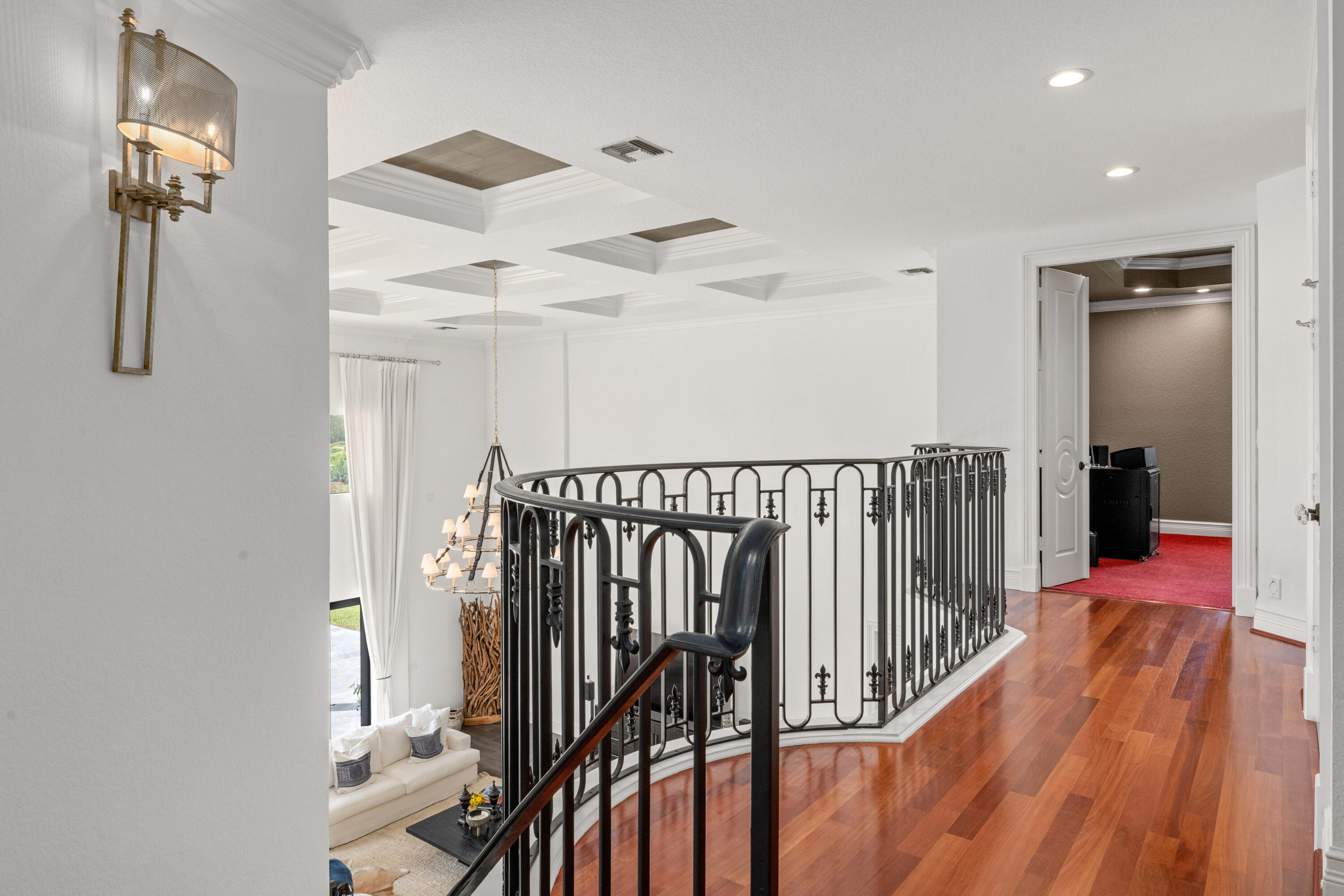 Upstairs landing with polished wood floors, ornate iron railing, and a view into the living room below.