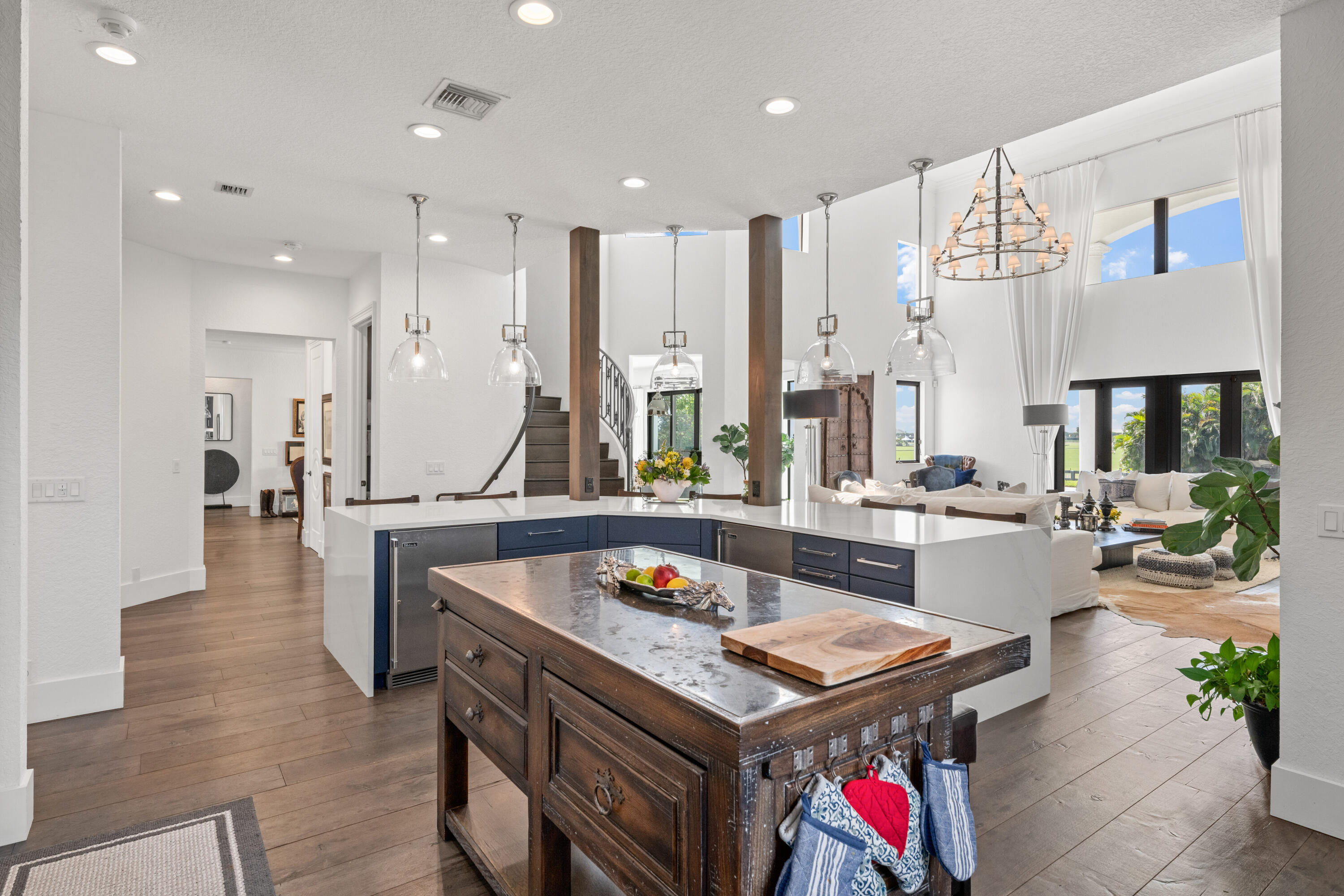 Open-plan kitchen with dark blue cabinets, a rustic wood prep table, and an adjoining living room.