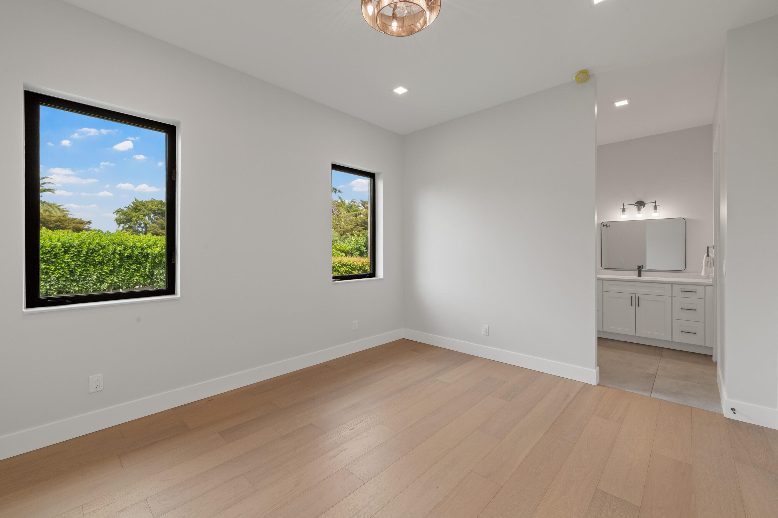 Unfurnished bedroom with two garden-facing windows and an ensuite bathroom vanity.
