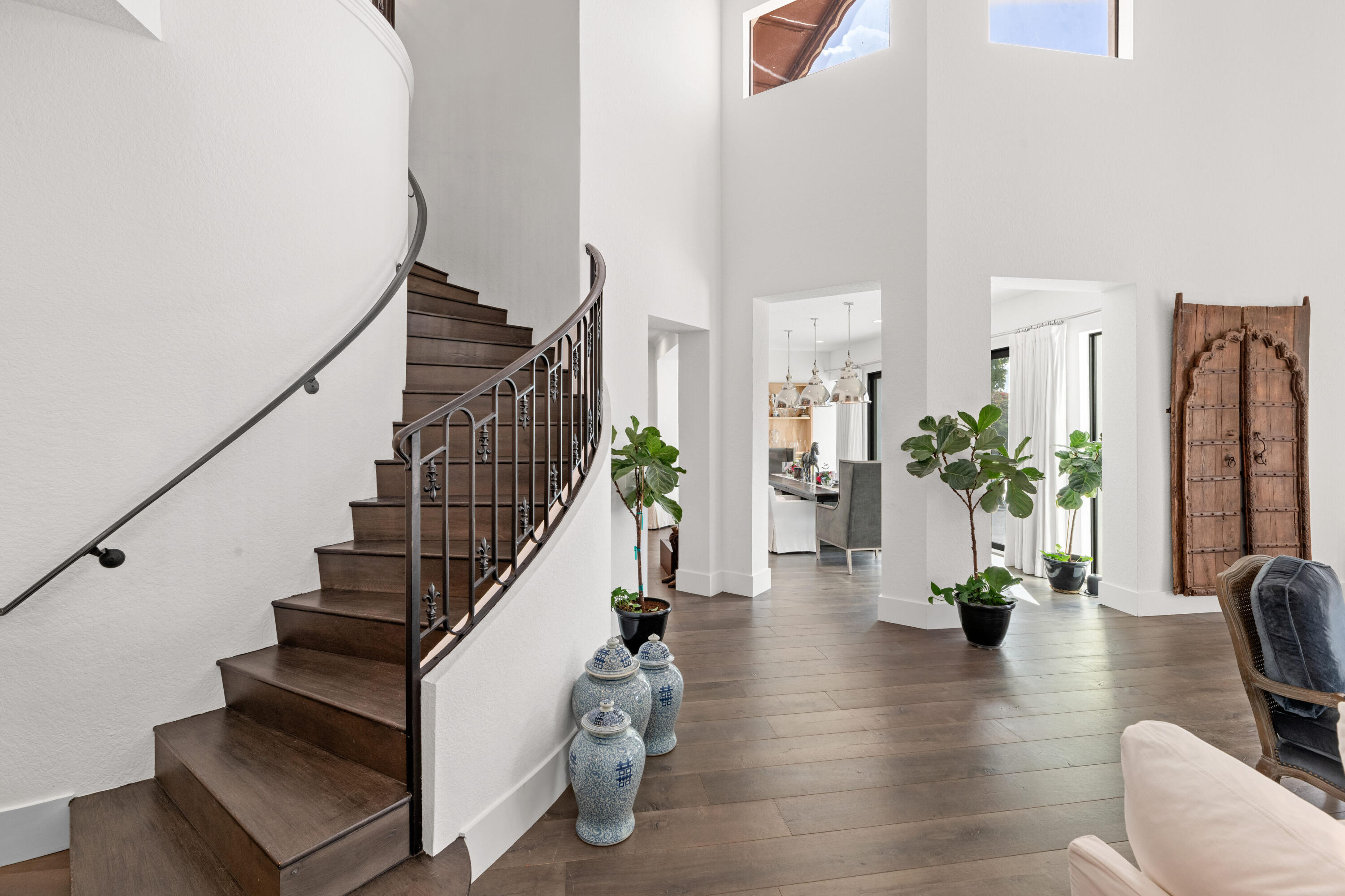 Entry foyer with a curved dark wood staircase, iron railing, and wide-plank floors.