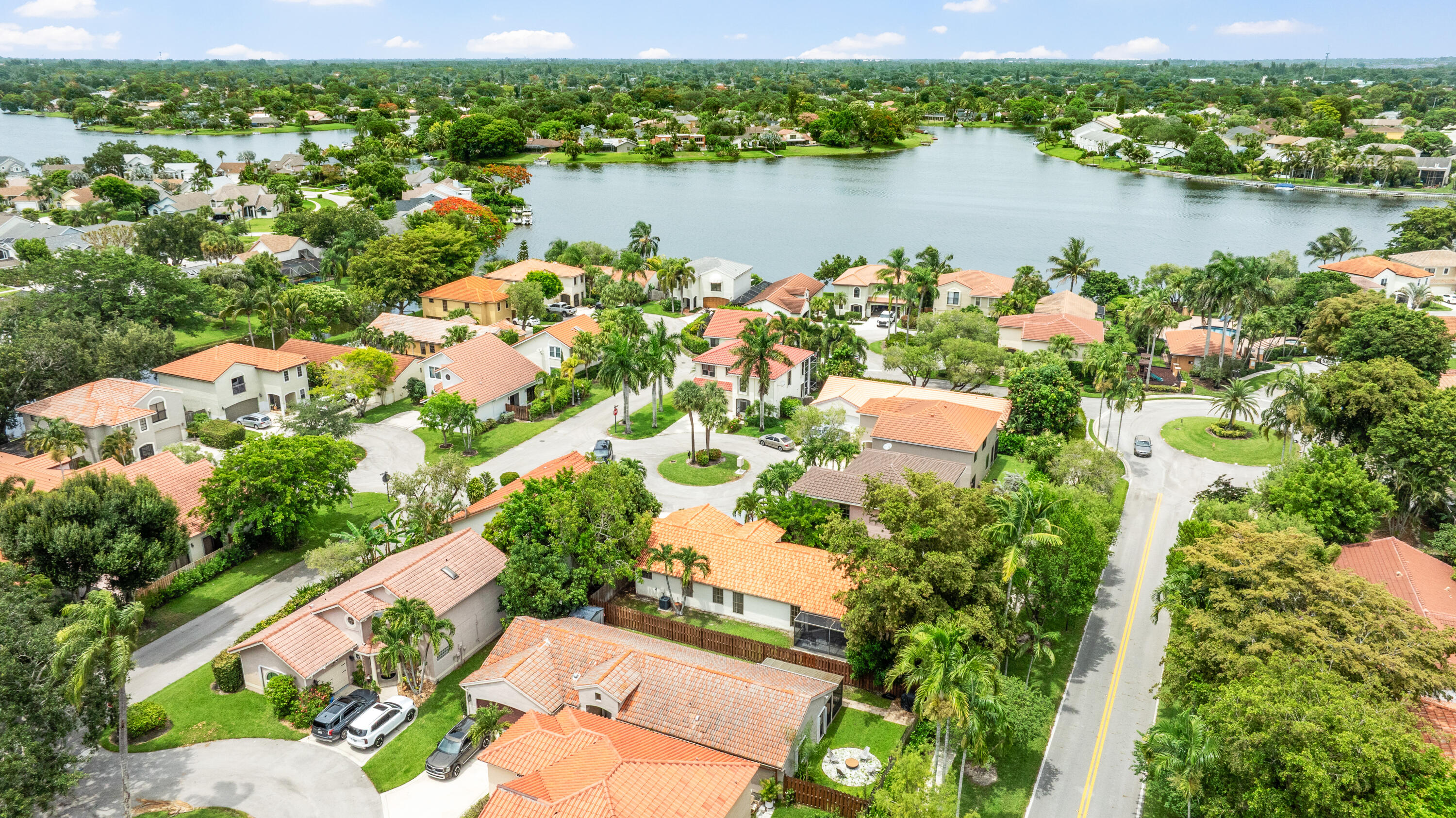 Aerial view of homes along a lake, with palm trees and winding neighborhood streets.
