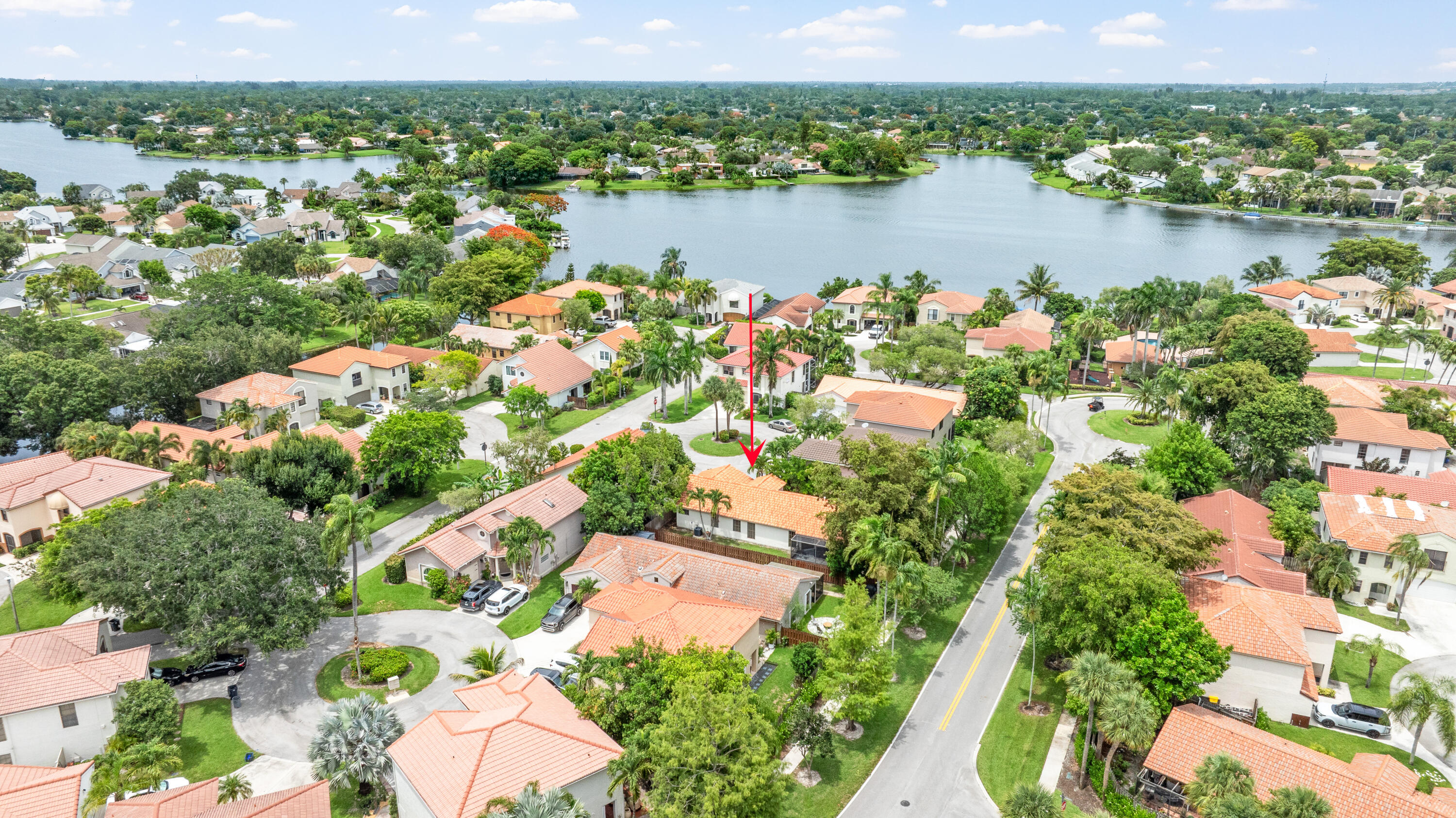 Aerial neighborhood view with a red arrow marking a home near the lake.