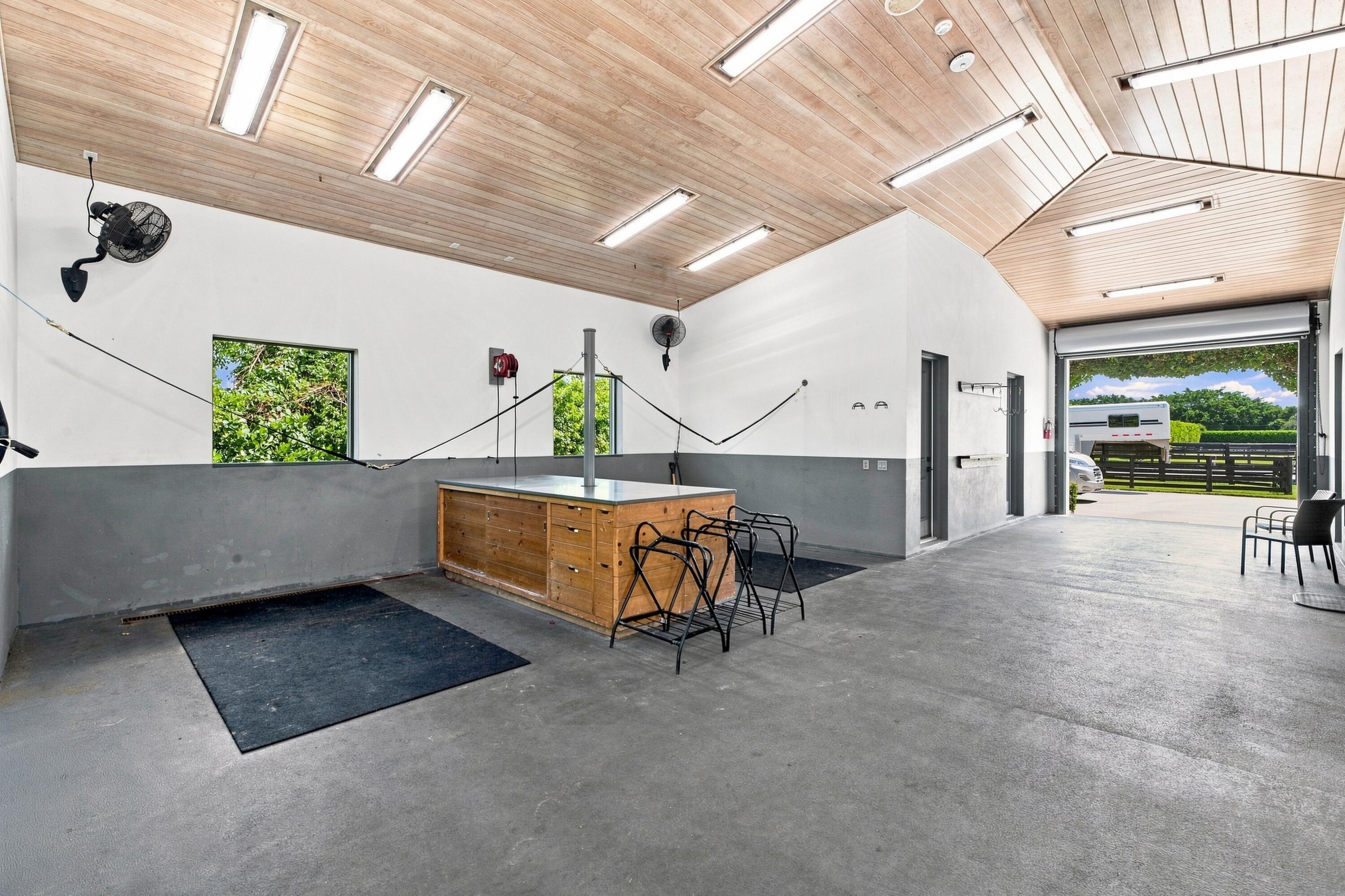 Horse barn grooming area with a wooden station, cross-ties, and an open door to the paddock.