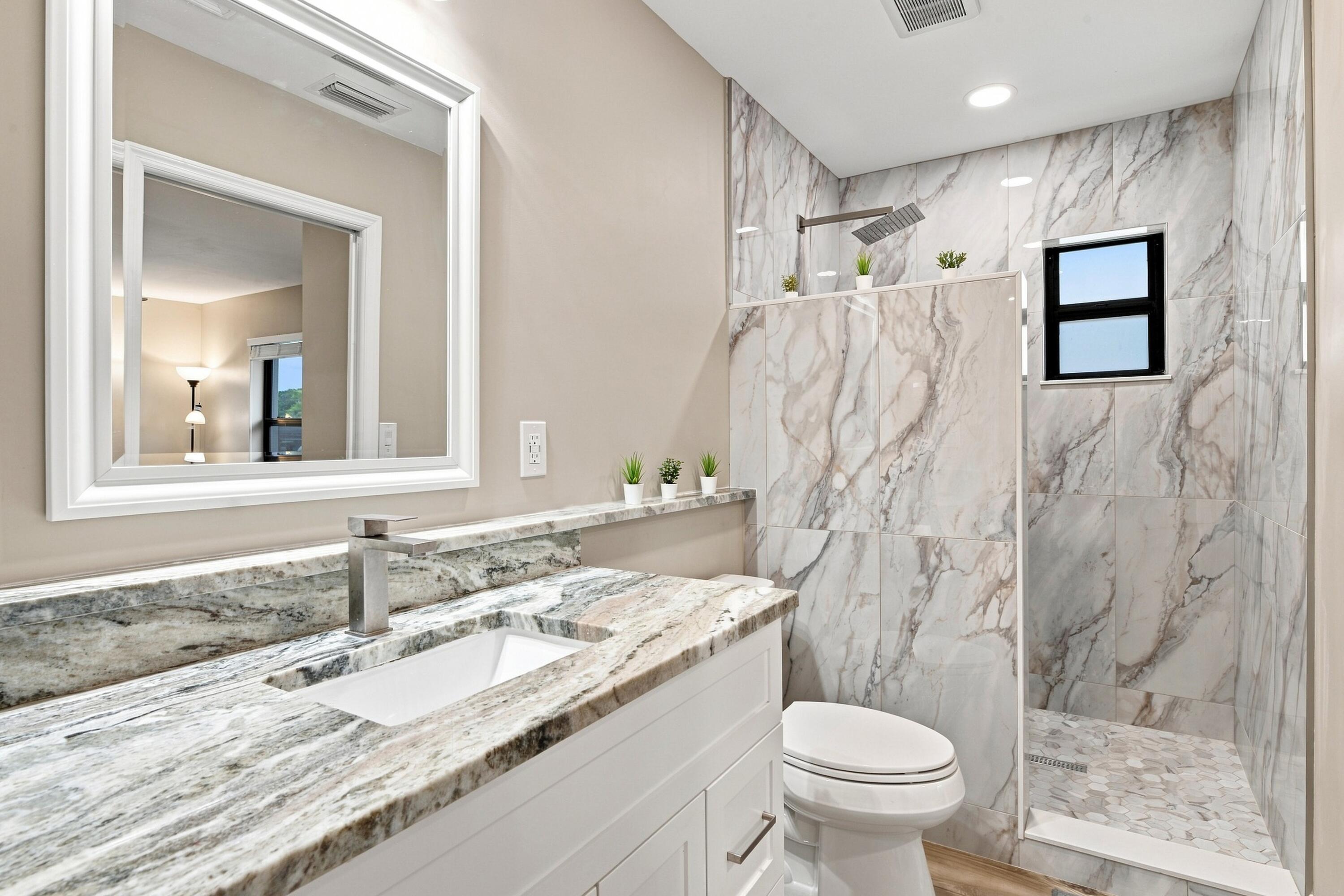 Bathroom with a marble vanity and glass-enclosed shower tiled in dramatic veined marble.
