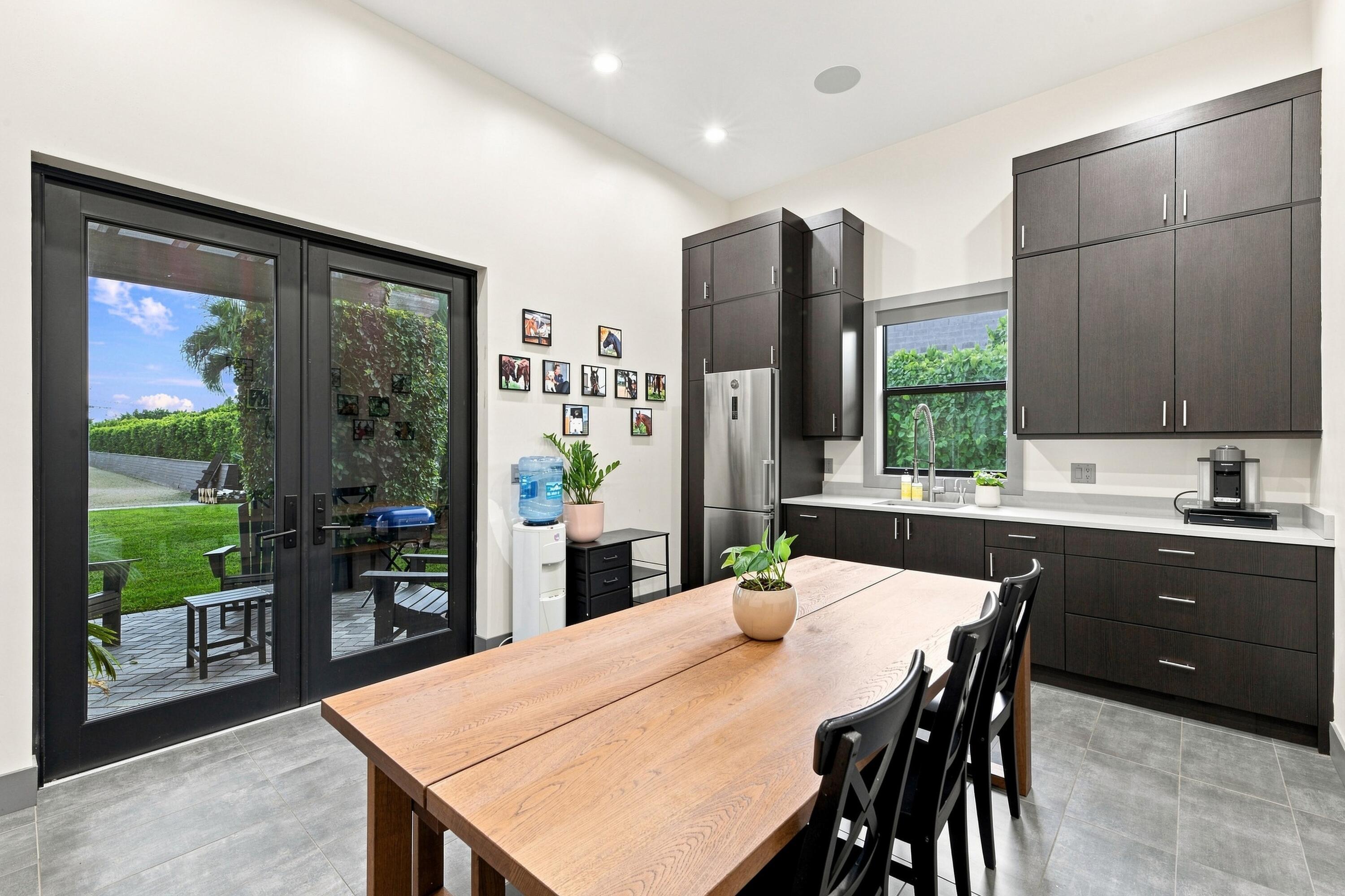 Kitchen and dining area with dark cabinetry, a wood table, and black-framed patio doors.