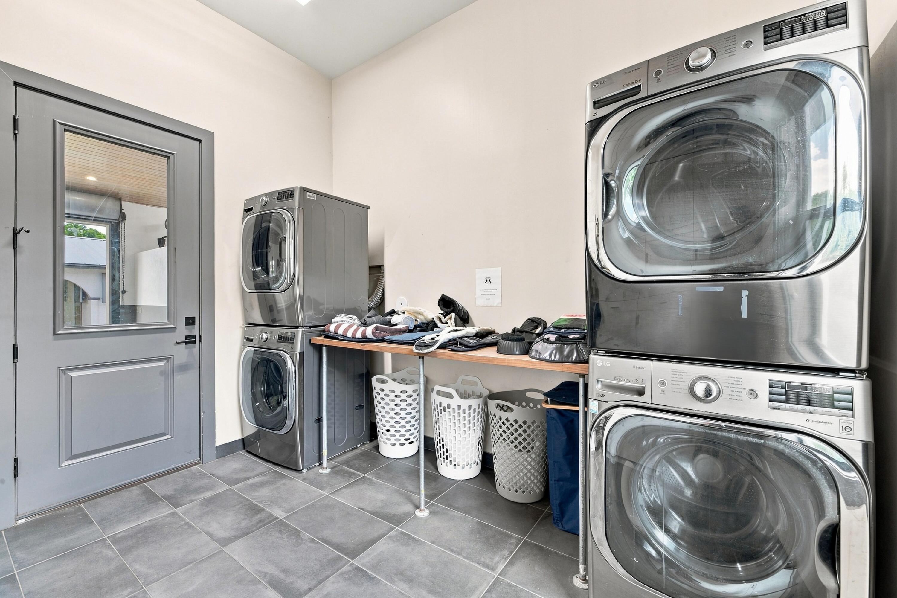 Laundry room with front-loading washer-dryer units, a laundry worktable, and baskets.