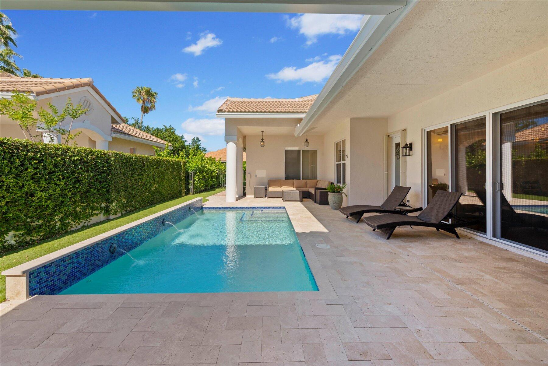 Backyard pool beside a covered patio with lounge chairs and outdoor seating.