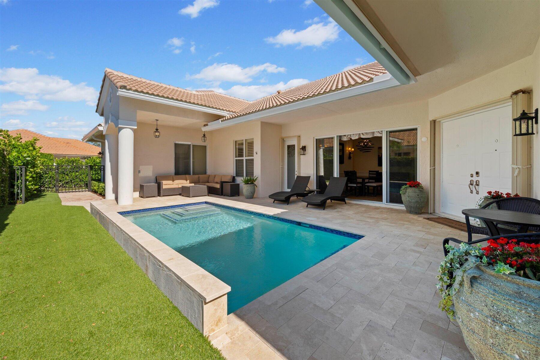 Backyard pool beside a covered patio with lounge seating and a tiled roof.