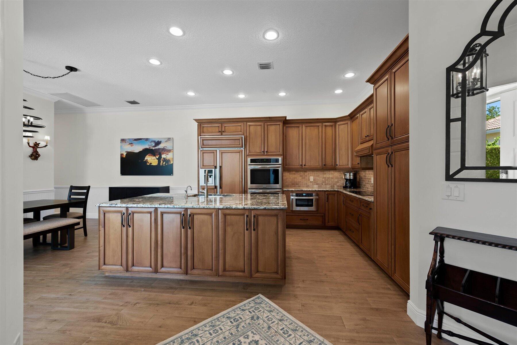 Kitchen with a large granite island, extensive wood cabinetry, and stainless steel appliances.