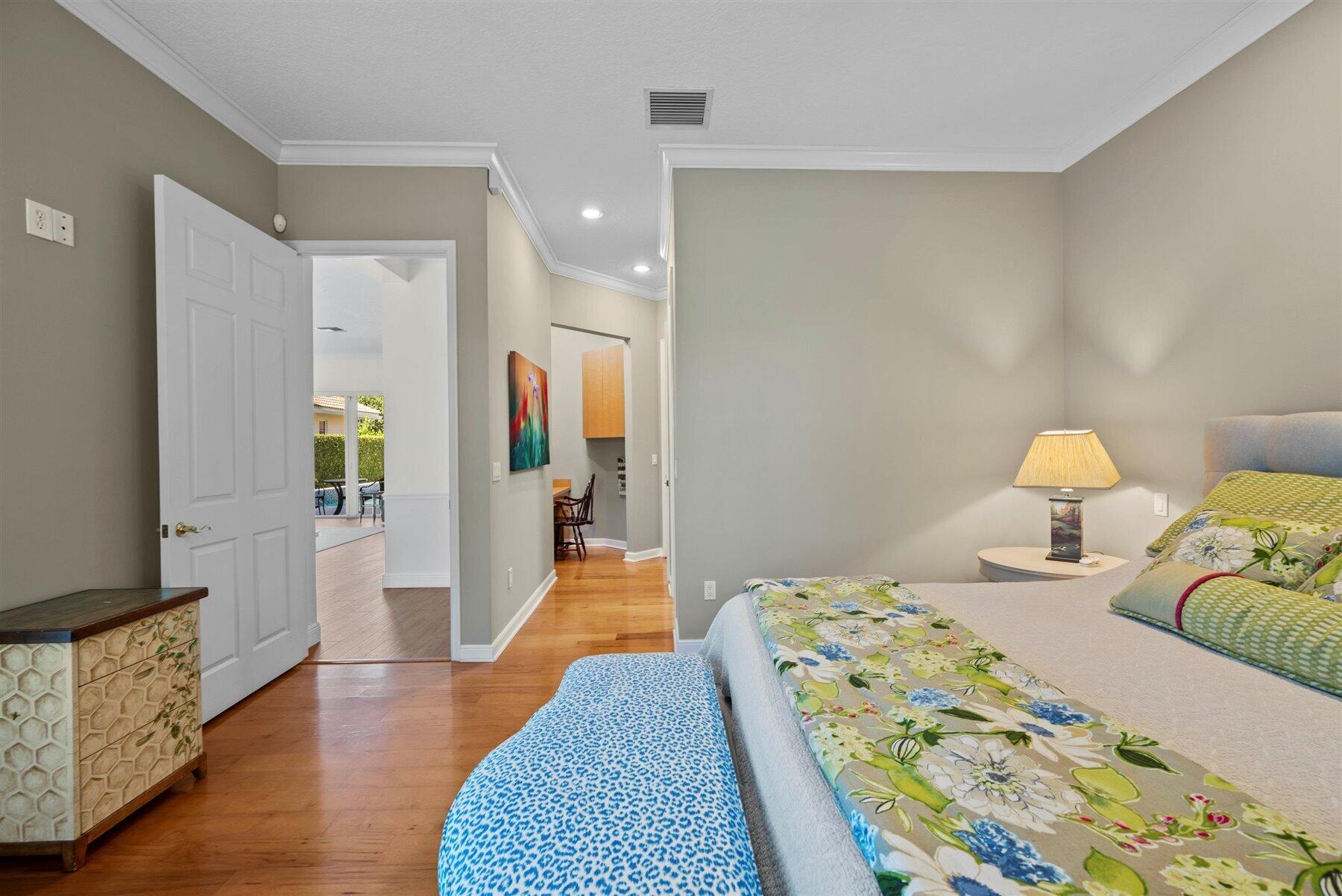 Bedroom with floral bedding, hardwood floors, and an open doorway to the hall.