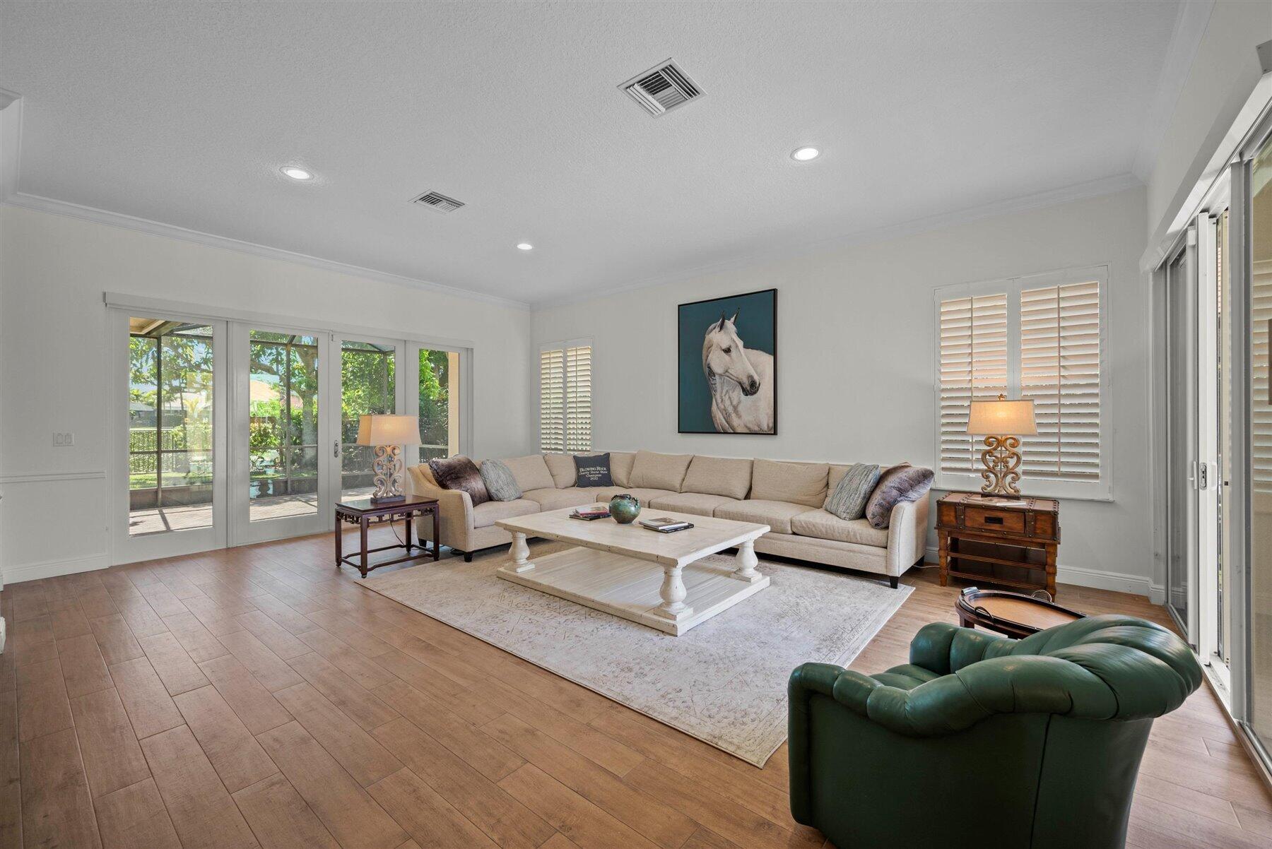 Furnished living room with a beige sectional, green leather armchair, and sliding glass doors to the patio.