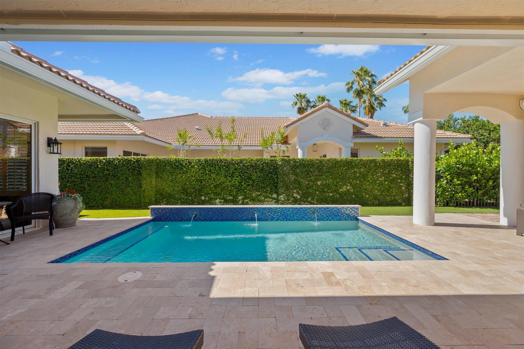 Backyard pool with a raised fountain wall, shallow sun shelf, and covered patio.