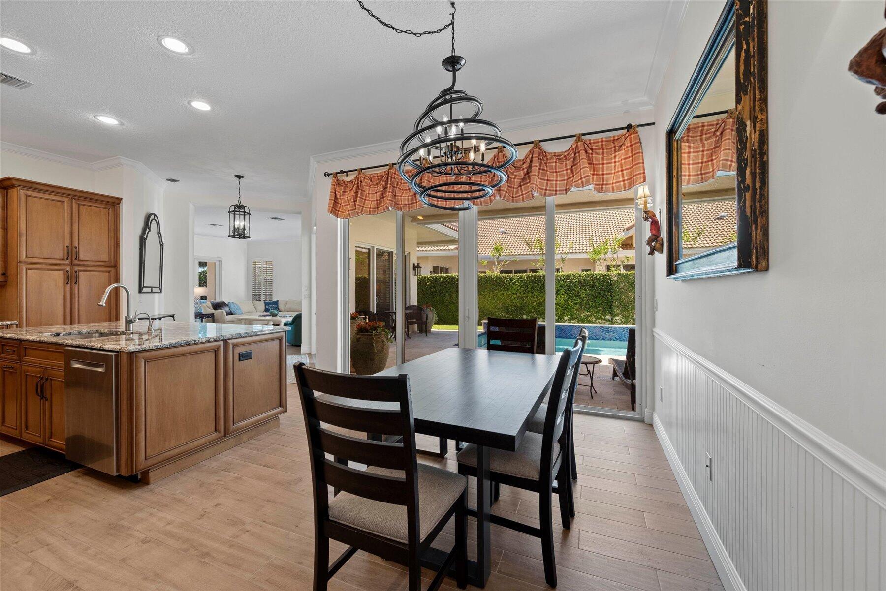 Kitchen and dining area with a granite island and sliding doors overlooking a patio pool.