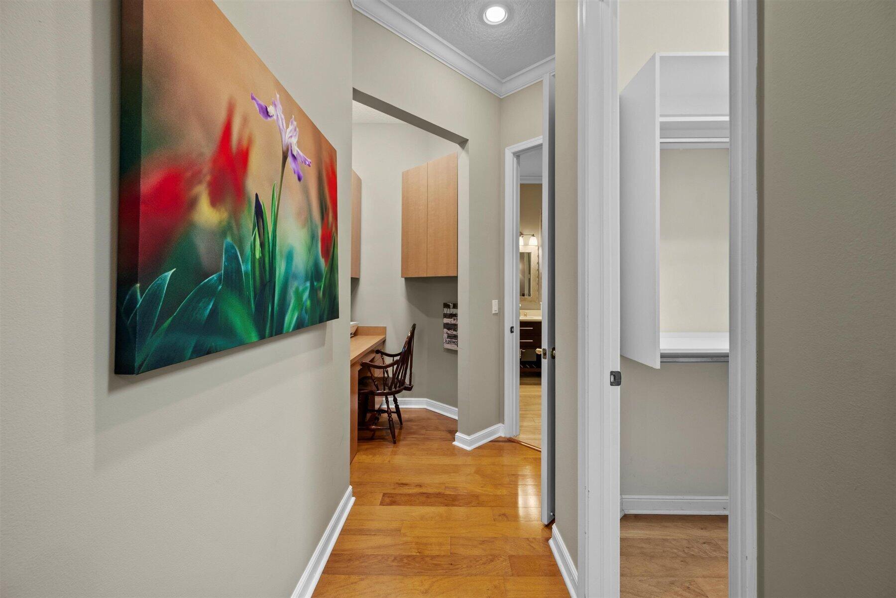 Hallway with colorful floral artwork, hardwood flooring, and a built-in desk nook.