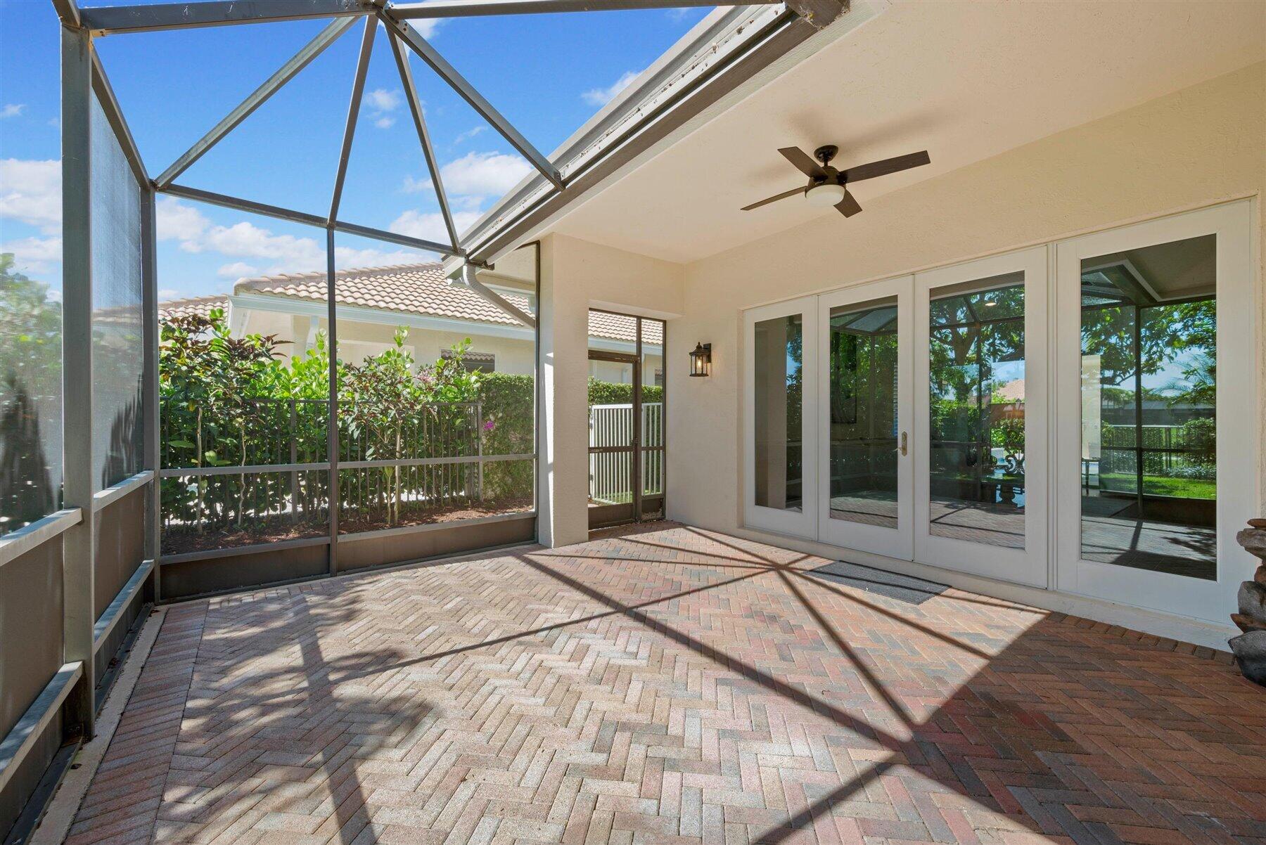 Screened patio with brick pavers, a ceiling fan, and sliding glass doors.