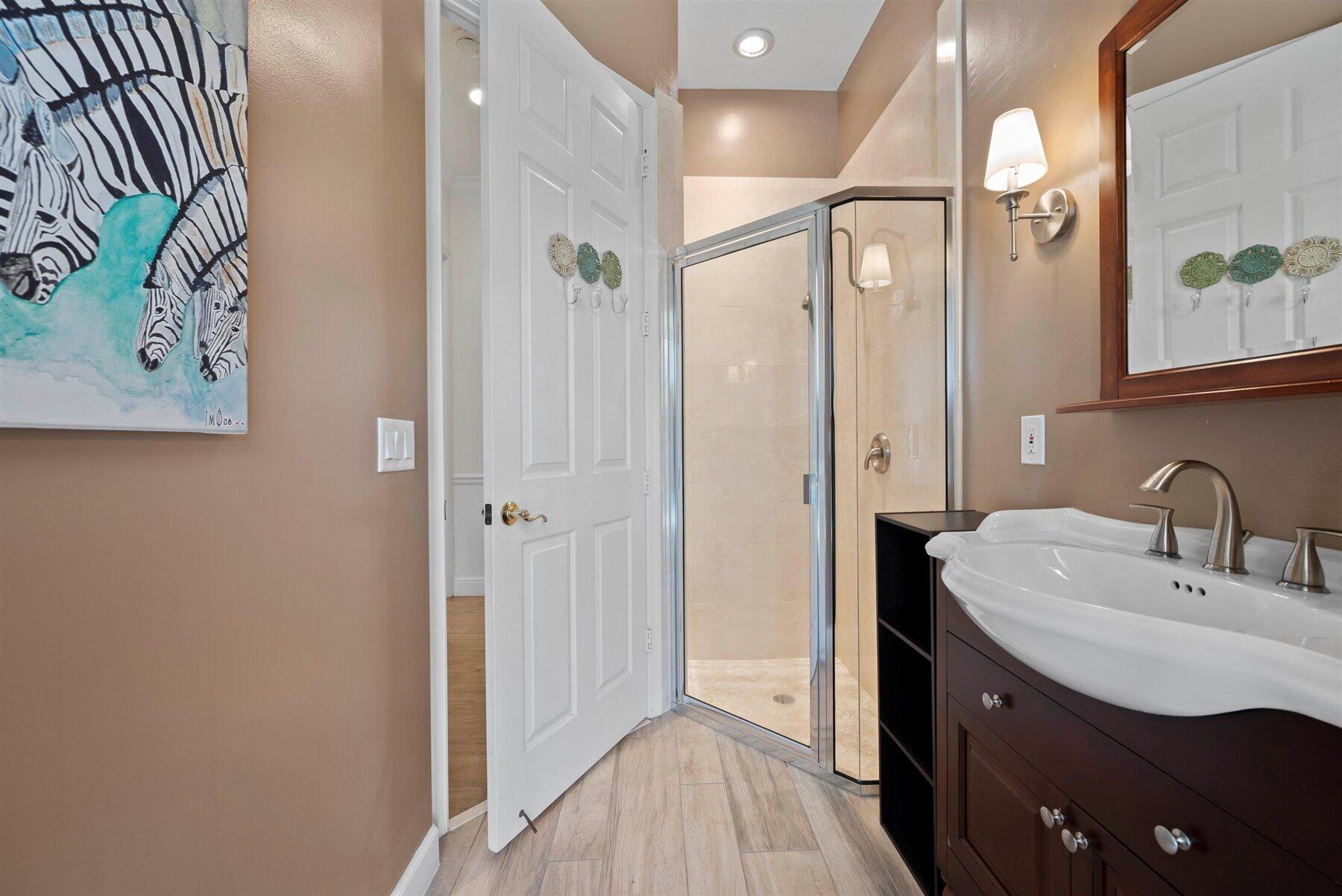 Bathroom with a glass-enclosed walk-in shower and dark wood vanity with a white vessel sink.