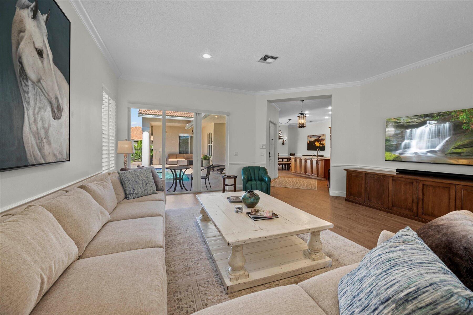 Living room with beige sofas, a white coffee table, and sliding doors opening to a poolside patio.