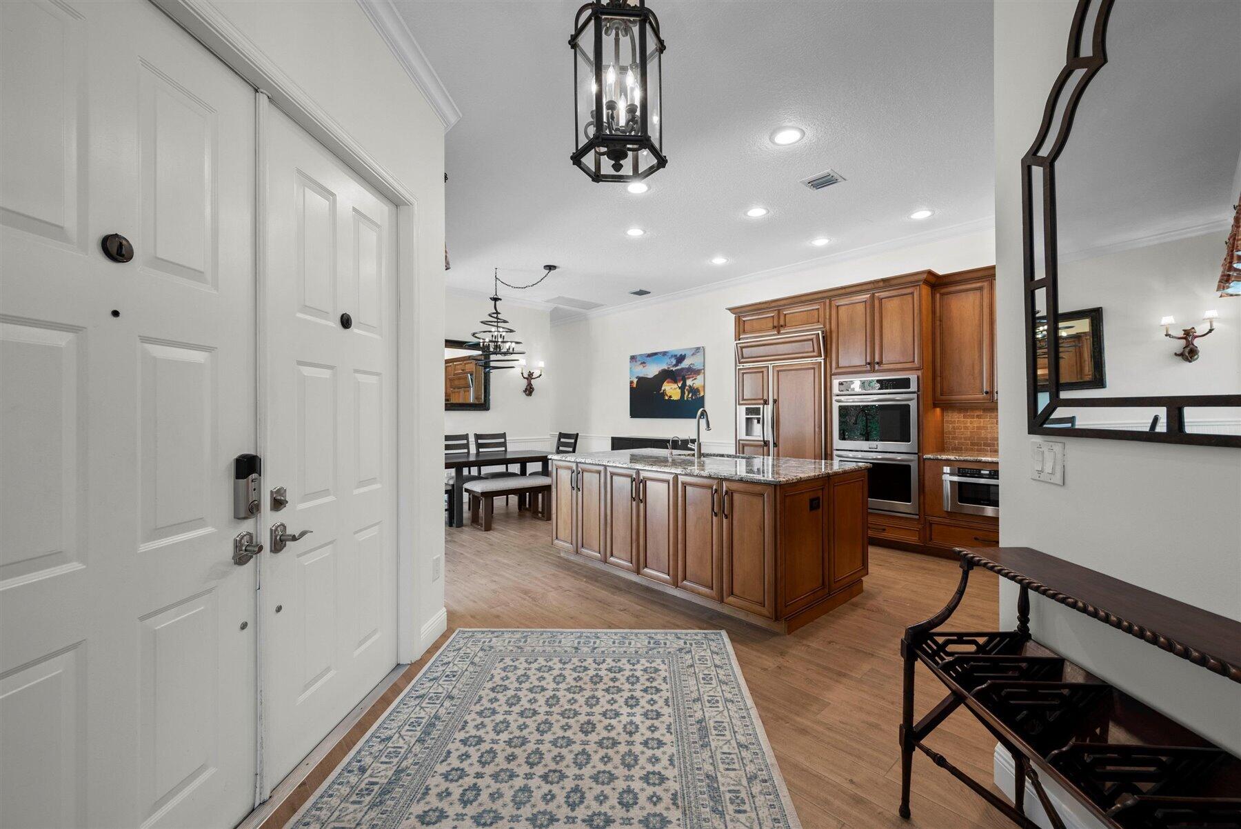 Entry foyer opening onto a wood-cabinet kitchen with a large island and dining area.