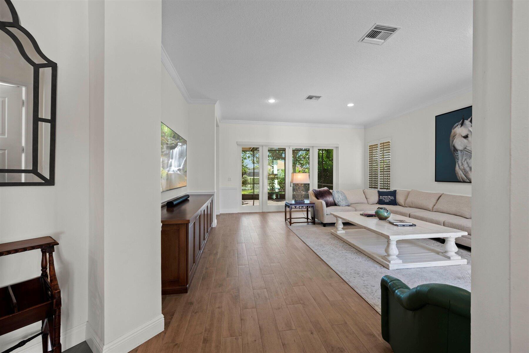 Living room with a beige sectional, white coffee table, and sliding glass doors to a green outdoor space.