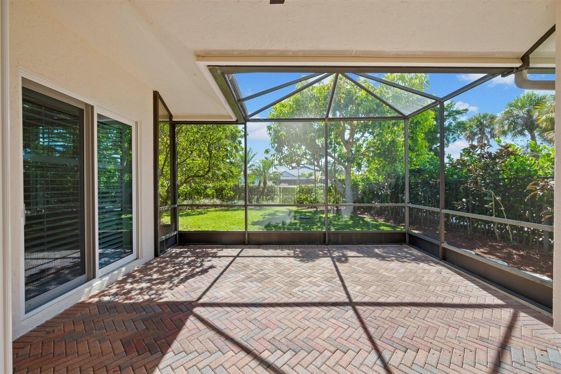 Screened patio with brick pavers and a leafy backyard.