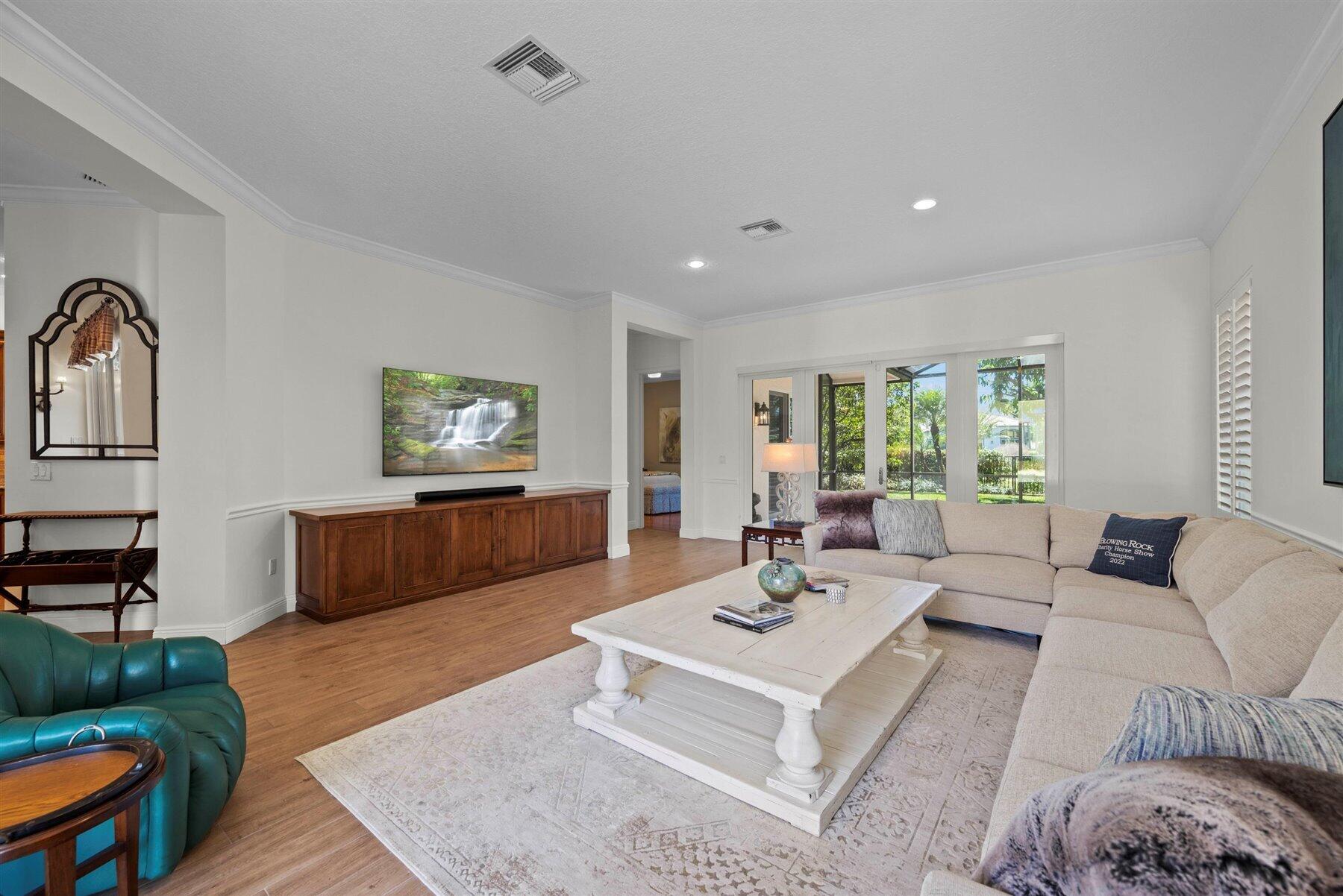 Living room with a beige sectional, teal armchair, white coffee table, and garden views through sliding doors.
