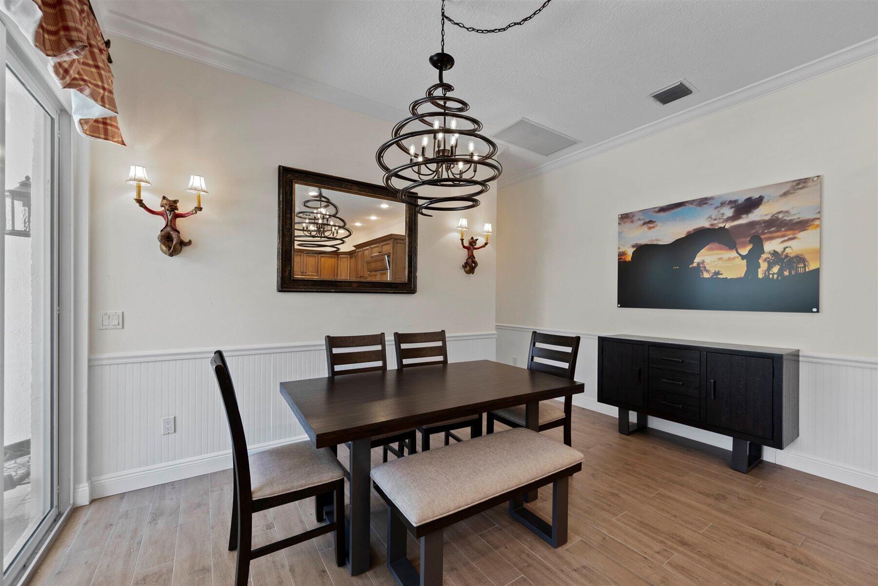 Dining room with a dark wood table, circular chandelier, and sliding glass doors.