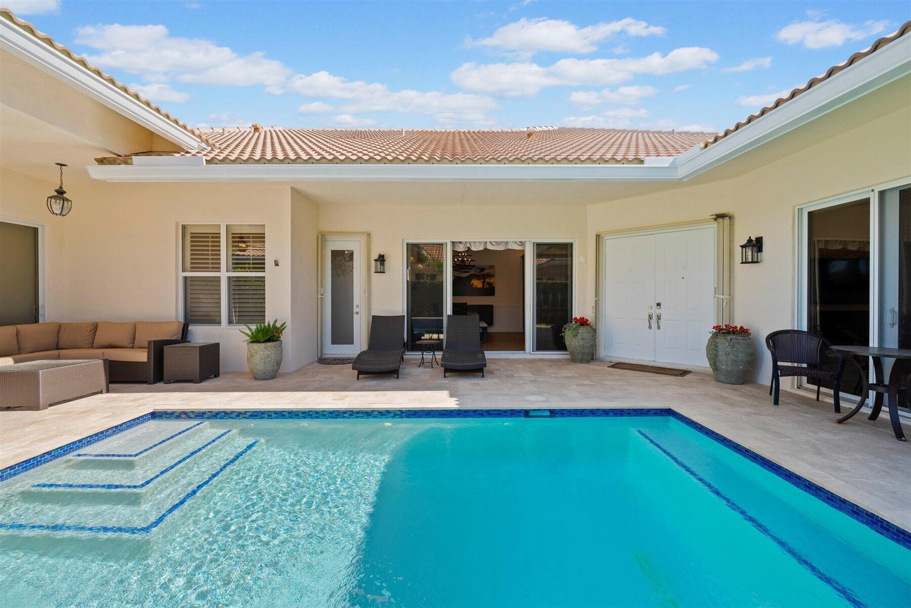 Backyard swimming pool with tiled steps and a covered patio furnished with outdoor seating.