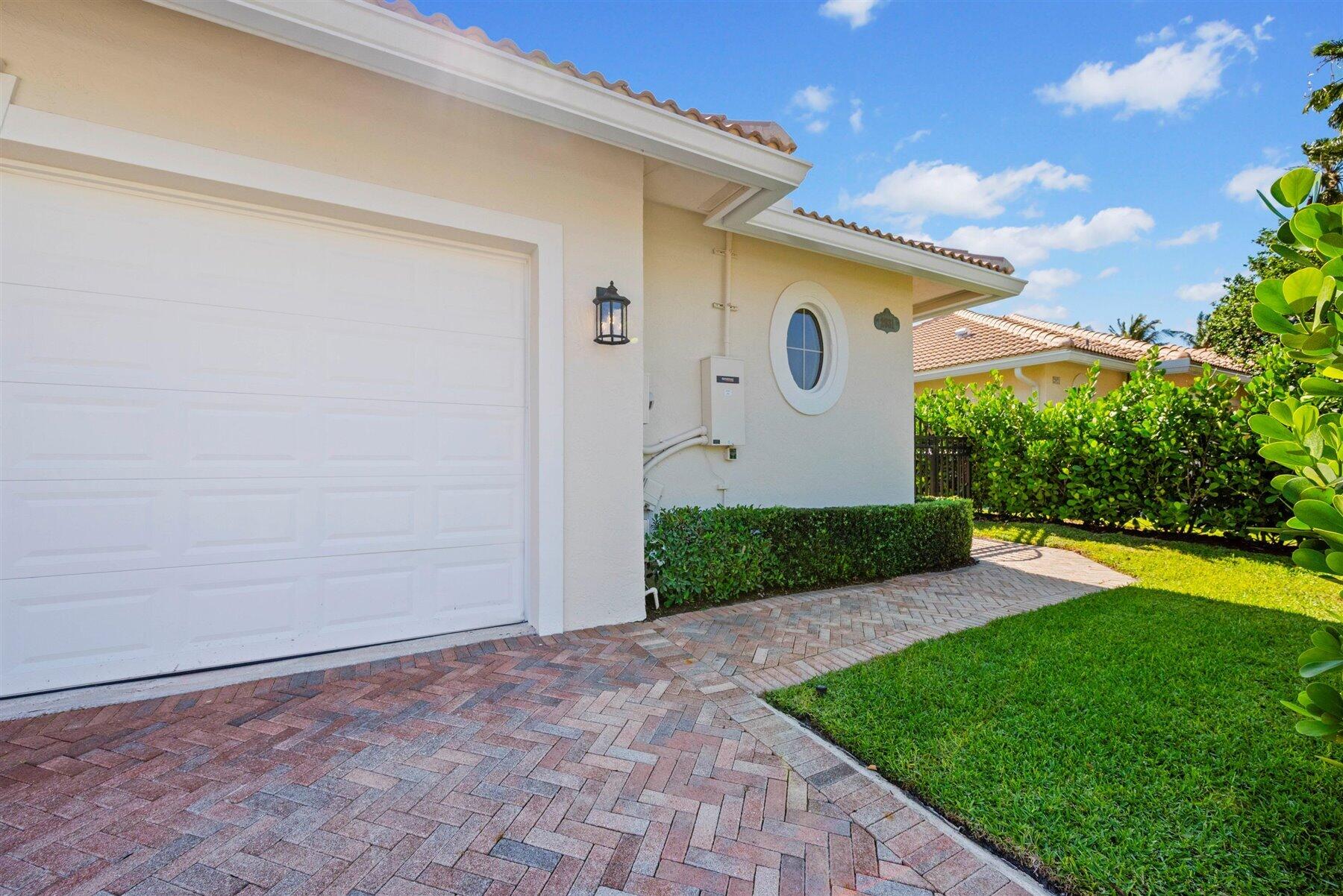 Home exterior with a white garage door, oval window, and curved brick-paver driveway.