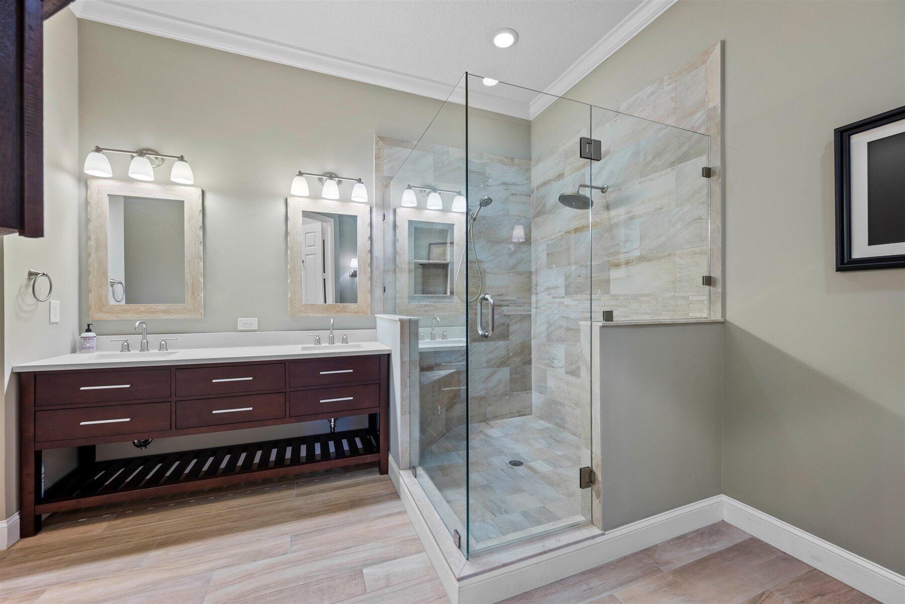 Bathroom with a dark wood double vanity and glass-enclosed tiled walk-in shower.