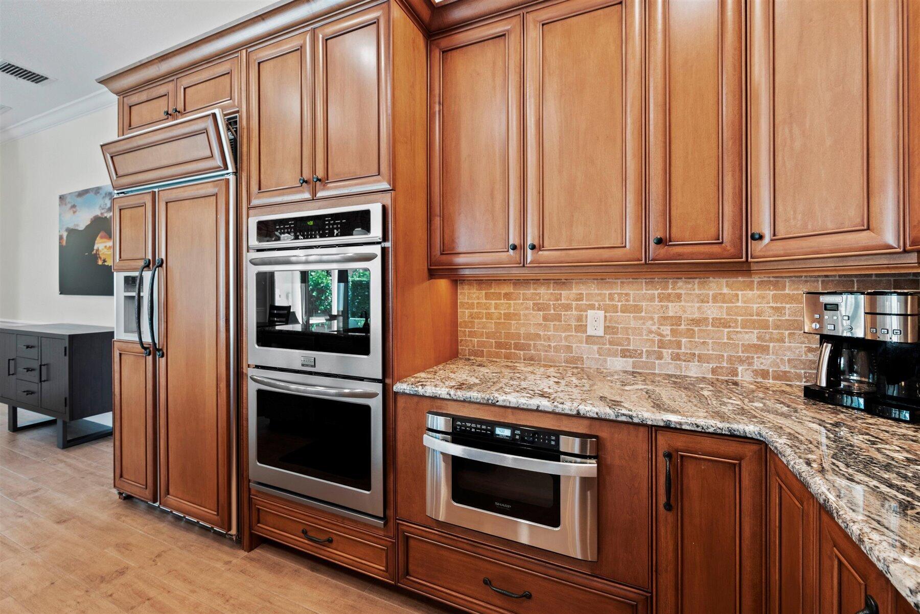 Kitchen with warm wood cabinets, granite counters, and stainless steel double ovens.