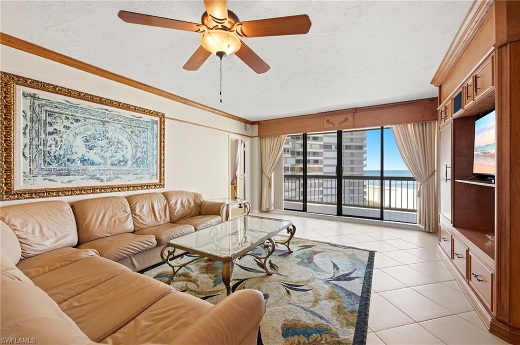 Living room with tan leather sofas and balcony views of the beach and ocean.