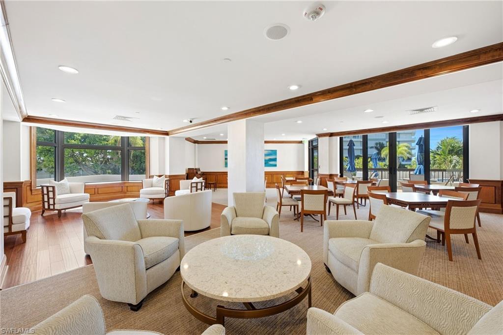 Furnished community lounge with a marble-topped table, dining area, and windows opening to a terrace.