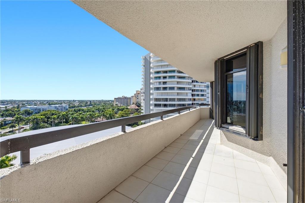 Condo balcony with tiled flooring and a view of high-rises, palm trees, and the surrounding neighborhood.