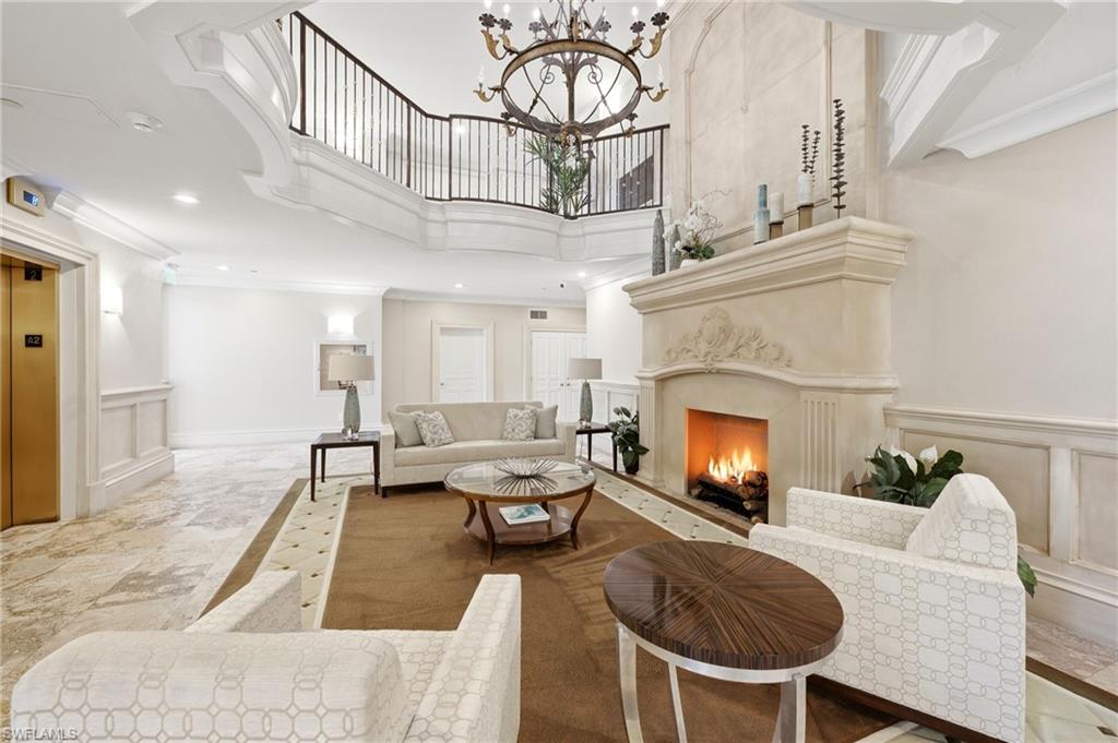 Condominium lobby with a lit fireplace, cream seating, and an open upper-level railing.