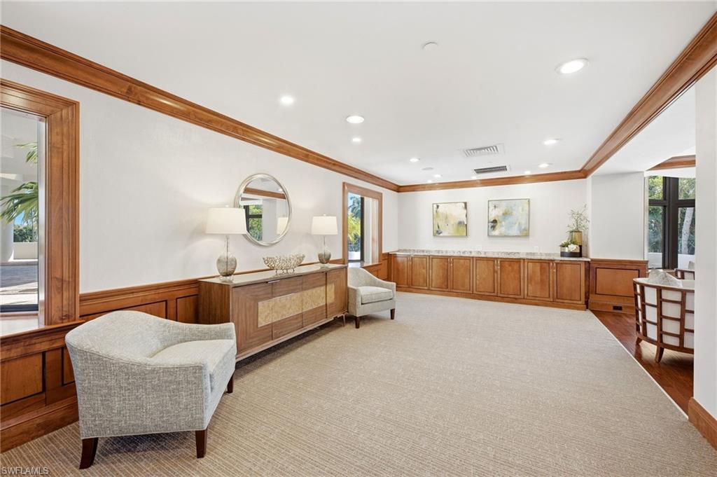 Furnished interior with wood cabinetry, upholstered chairs, and a large beige rug.