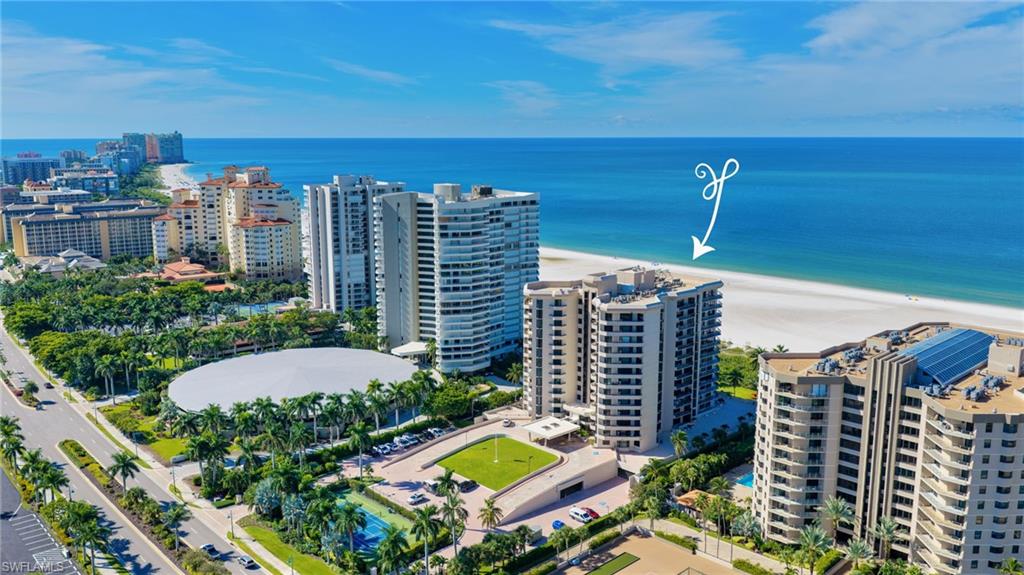 Aerial view of beachfront condominium towers, with an arrow marking the featured building beside the Gulf.