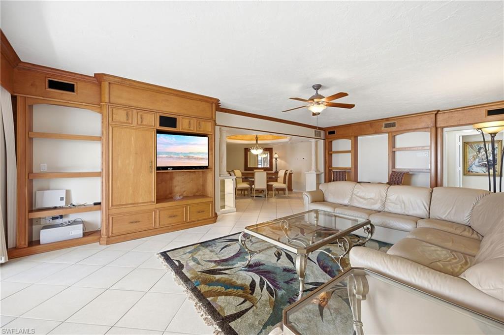 Living room with a white sectional, glass coffee table, patterned rug, and honey-colored built-in cabinetry.