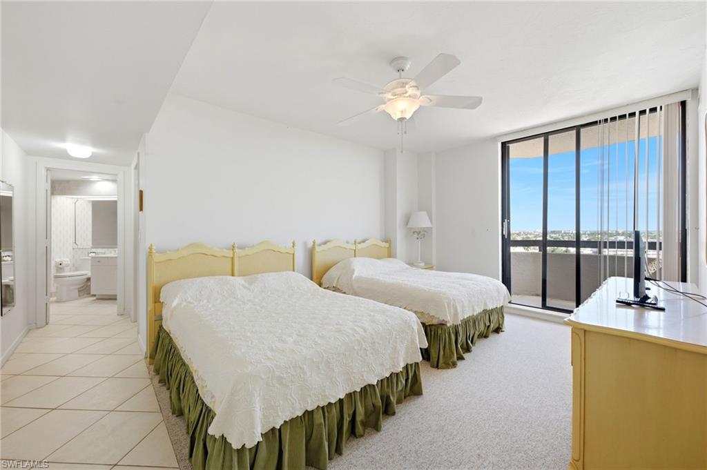 Bedroom with two beds, pale yellow headboards, and sliding glass doors to a balcony.