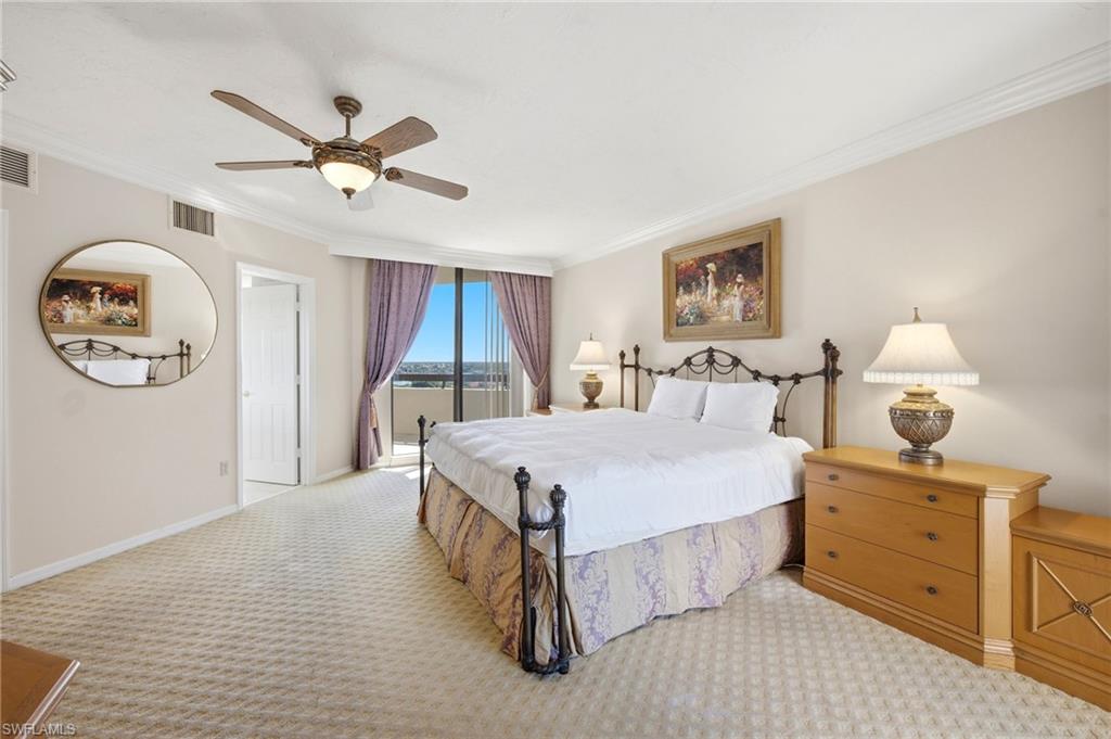 Furnished bedroom with a king bed, ceiling fan, and sliding glass door overlooking water.