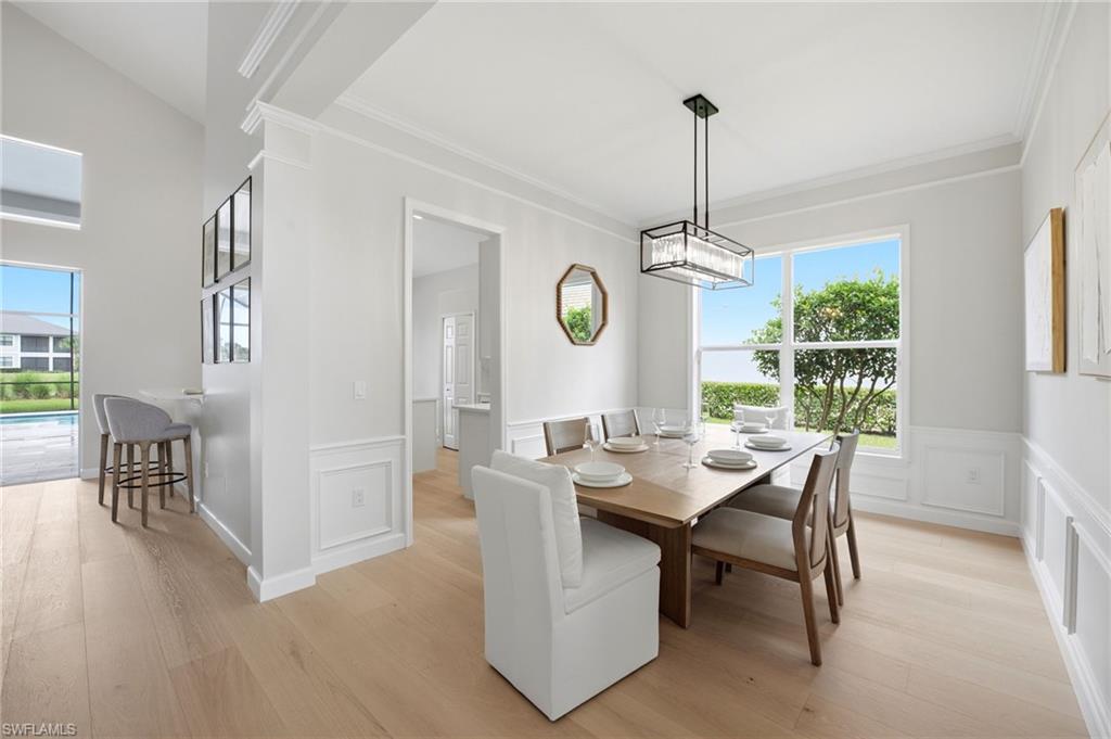 Dining room with a wood table, mixed chairs, and a large window overlooking the yard.