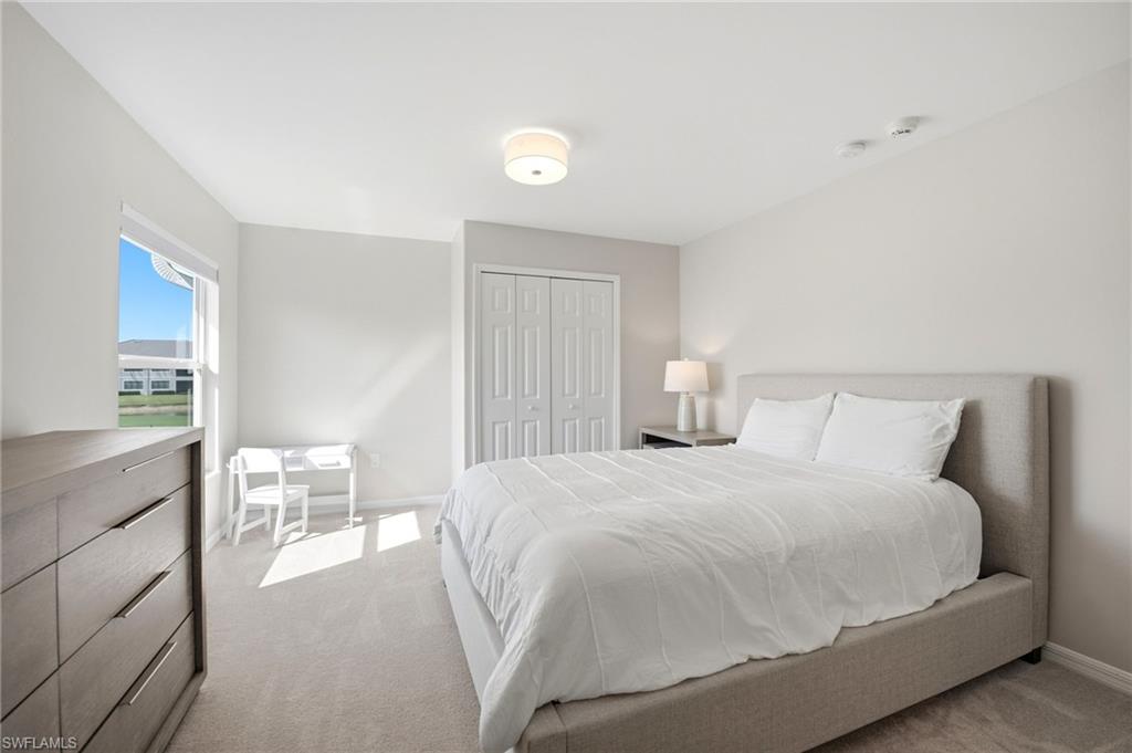 Bedroom with a gray upholstered bed, white bedding, and sunlight through the window.
