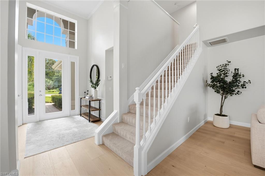 Entry foyer with a tall front-door transom and carpeted staircase with white railing.