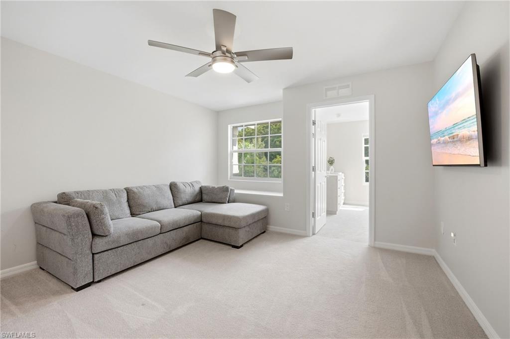 Sitting room with a gray sectional sofa, ceiling fan, and wall-mounted television.