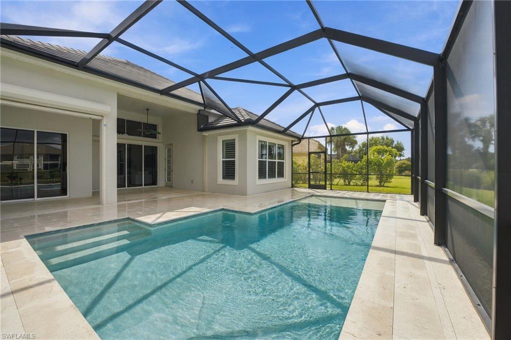 Swimming pool and tiled patio under a screened enclosure, with lawn and trees beyond.