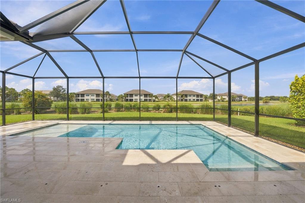 Screened swimming pool and stone deck overlooking a lake and neighboring homes.