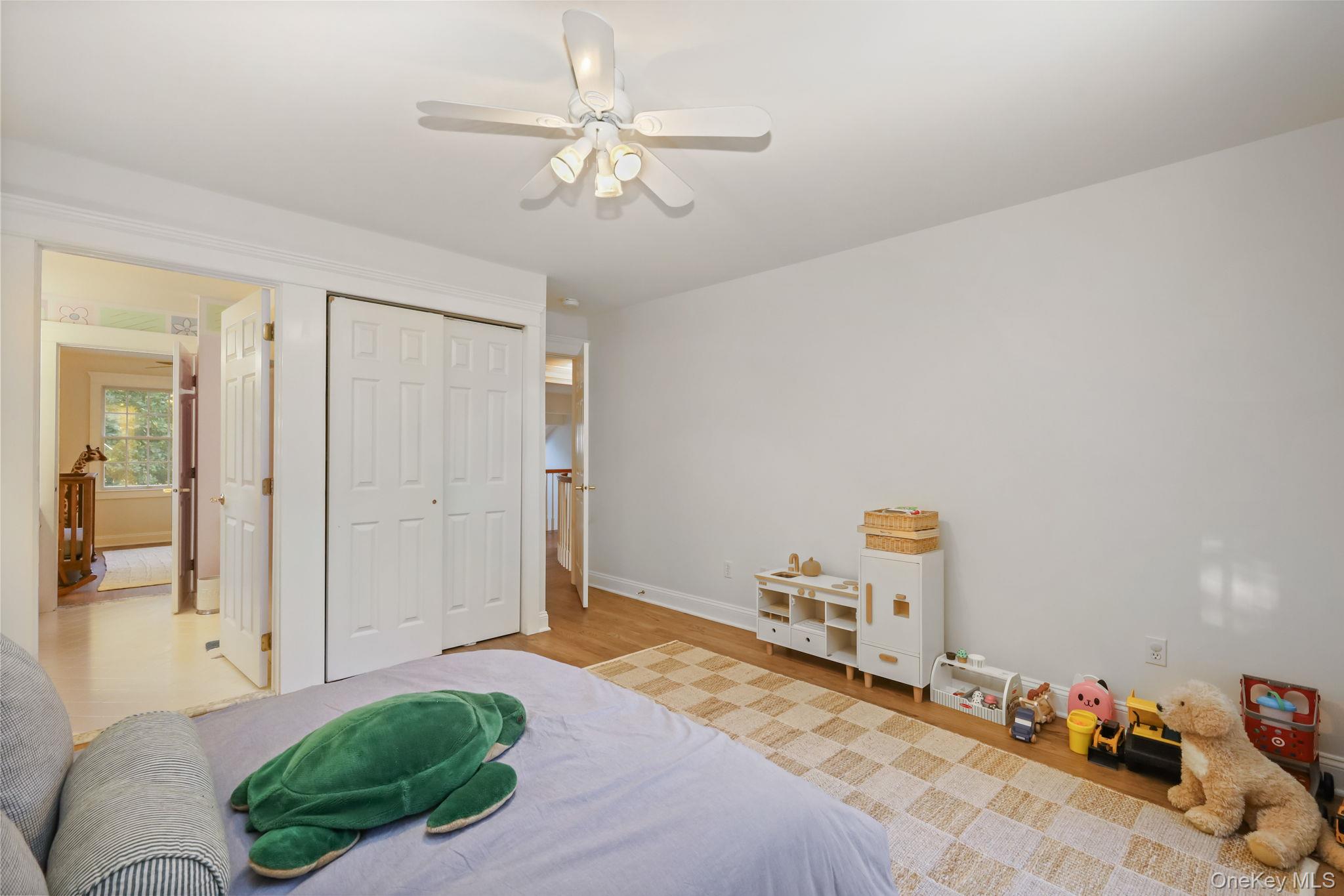 Furnished bedroom with sliding closet doors, a green turtle plush, and children’s toys.