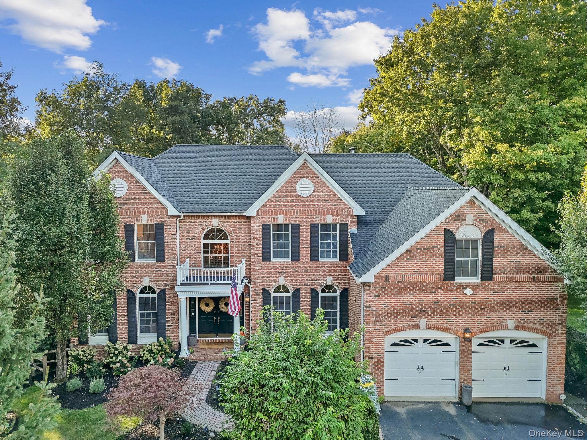 Two-story brick home with black shutters, a double garage, and landscaped front yard.