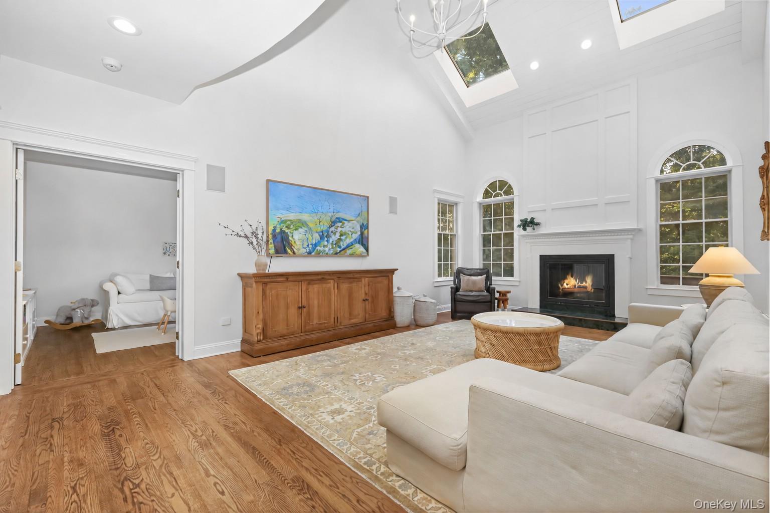 Vaulted living room with skylights, arched windows, a fireplace, and a cream sectional.